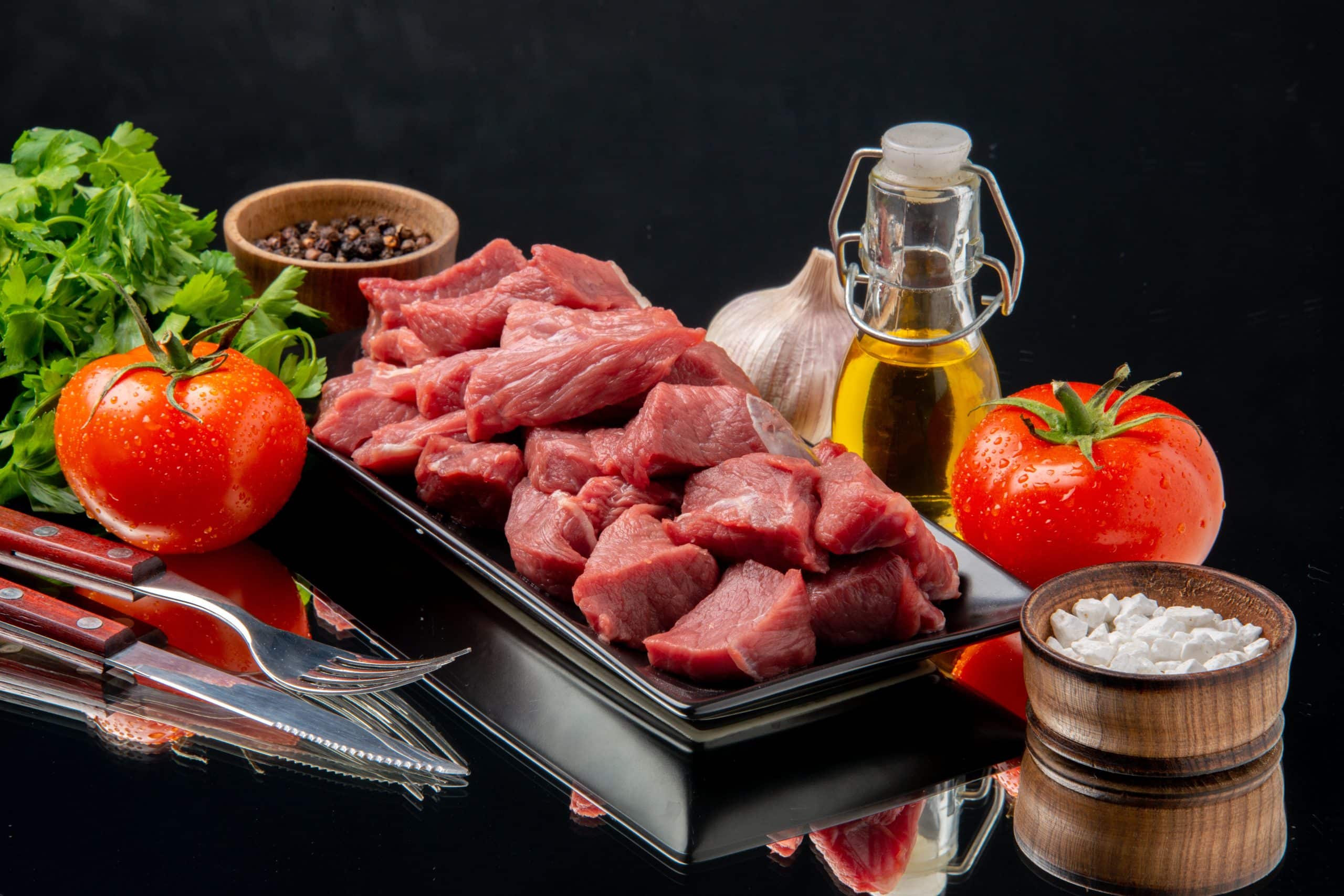 front-view-fresh-meat-slices-inside-black-tray-with-tomatoes-greens-black-table